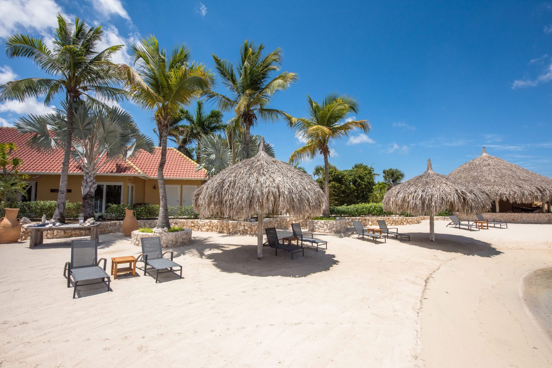The beach with palapa's, palm trees and beach beds at Isla Kiniw