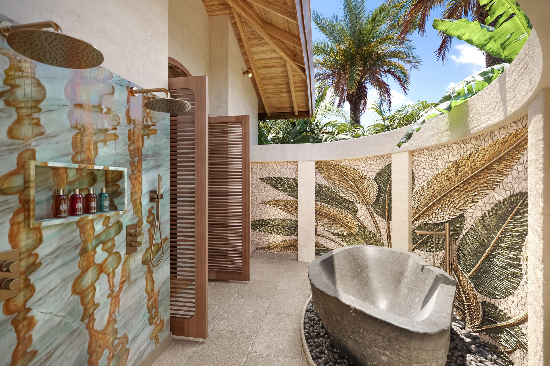Outdoor shower and natural stone bath surrounded by tropical gardens in the Oceanfront Pool Suite at Baoase Curaçao